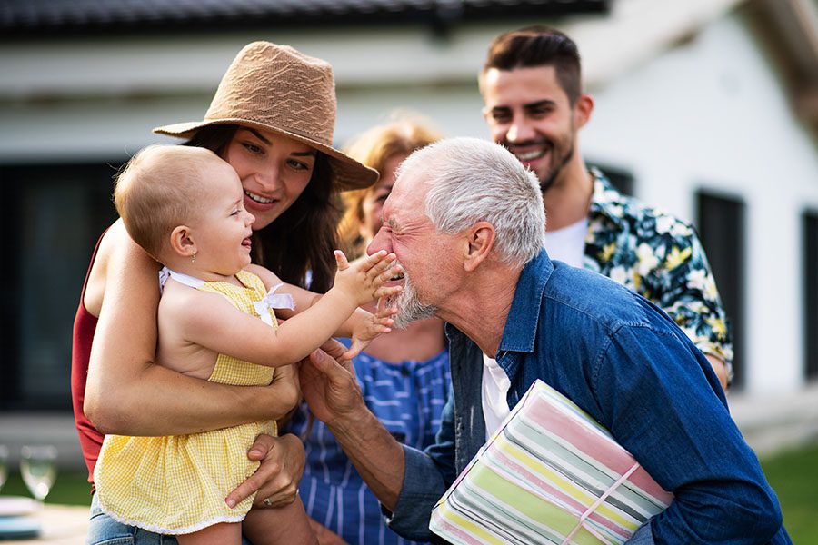 About Our Agency - Happy Baby Touching Grandfathers Face With Family Outside