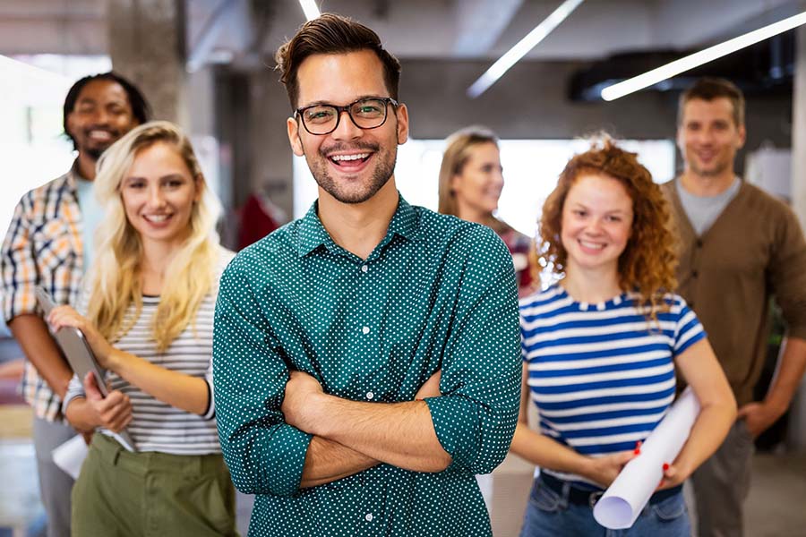 Employee Benefits - Group Of Smiling Employees Standing In Office